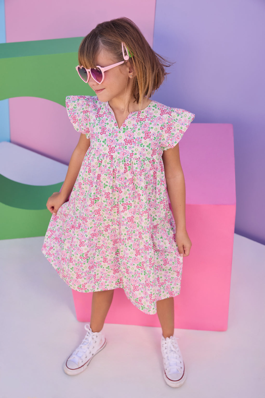 Model can be seen wearing a woven dress in a pink/green floral print. Dress features a slight v-neckline, angel sleeves, and button closure along back for a secure but comfy fit. 