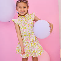 Model can be seen wearing a woven yellow/pink floral top that features angel sleeve details, high ruffle neckline, and button closure on back for a comfy but secure fit. Matches back perfectly with the tiered skort in the same floral print to complete the look.