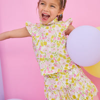 Model can be seen wearing a woven yellow/pink floral top that features angel sleeve details, high ruffle neckline, and button closure on back for a comfy but secure fit. Matches back perfectly with the tiered skort in the same floral print to complete the look.