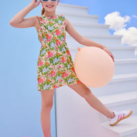 Model can be seen wearing a woven green/pink/orange/light blue floral dress that features two cutout features on the sides of the dress to give it an elevated/big girl feel. 