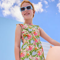 Model can be seen wearing a woven green/pink/orange/light blue floral dress that features two cutout features on the sides of the dress to give it an elevated/big girl feel. 