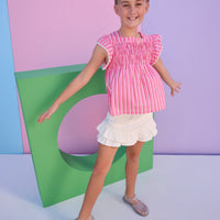 Model can be seen wearing denim mini skirt in an ivory denim that features two  tiered ruffle detail at bottom and button closure at waist. Skirt pairs back perfectly with most tops, and can be seen paired back with a red/pink/white stripe woven top. 