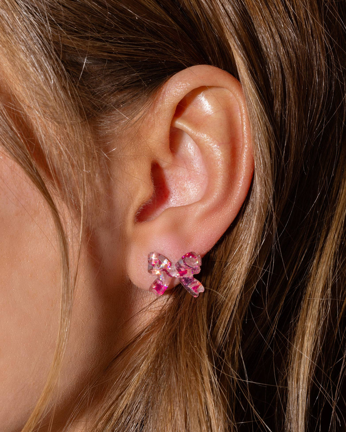 Close-up of an ear wearing a pink bow earring