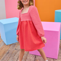 Model can be seen wearing a thick knit long sleeve dress that features a square neckline, elastic cuffs at sleeve, and a mix and match pink and red stripe detail to elevate the look.