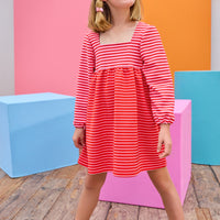 Model can be seen wearing a thick knit long sleeve dress that features a square neckline, elastic cuffs at sleeve, and a mix and match pink and red stripe detail to elevate the look.