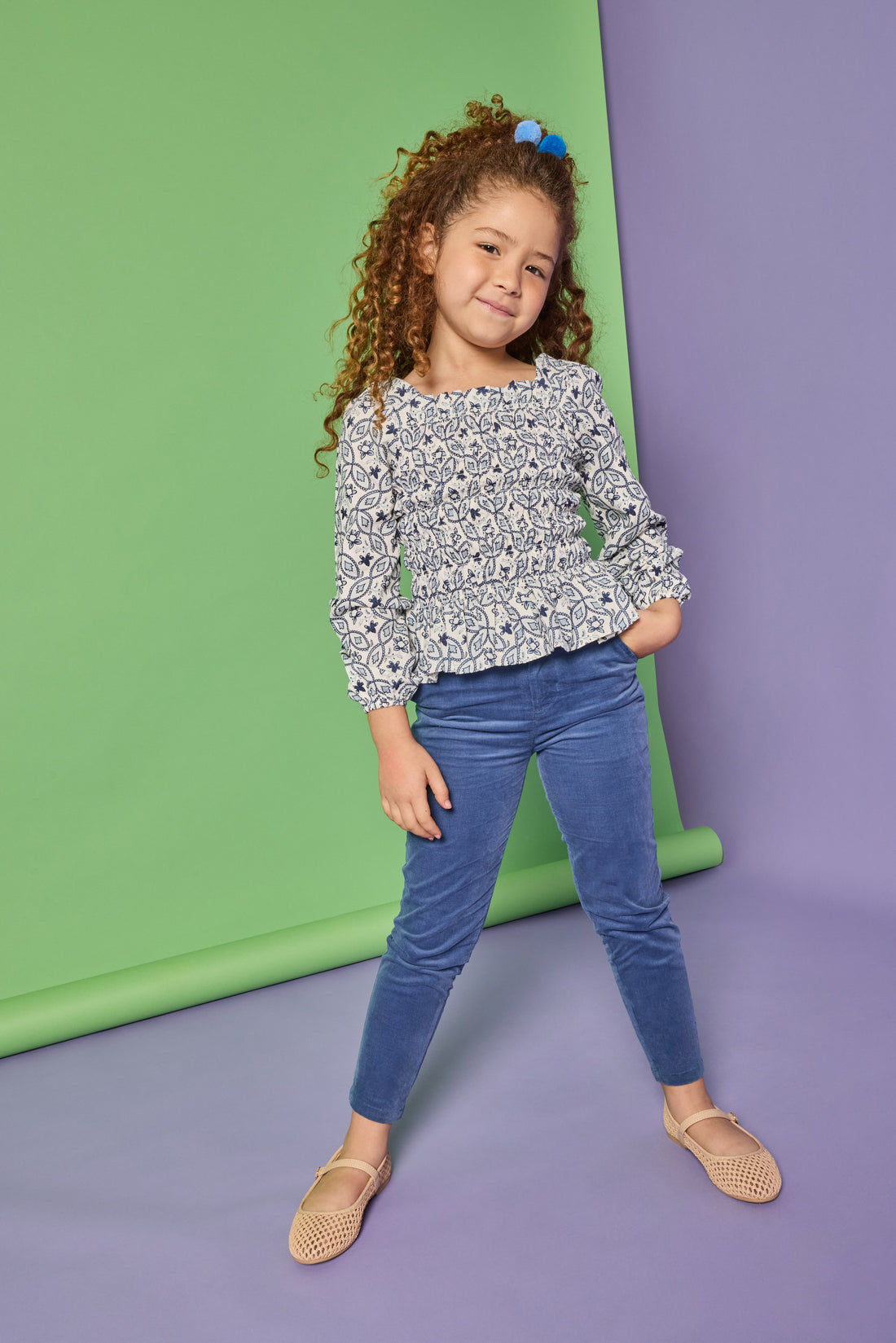 Model can be seen wearing a long sleeve woven top that features elastic ruching throughout the body of the shirt. Made of a blue and white floral print, the top pairs back perfectly with our dusty blue corduroy pants that have two pockets and button closure at waistband. 