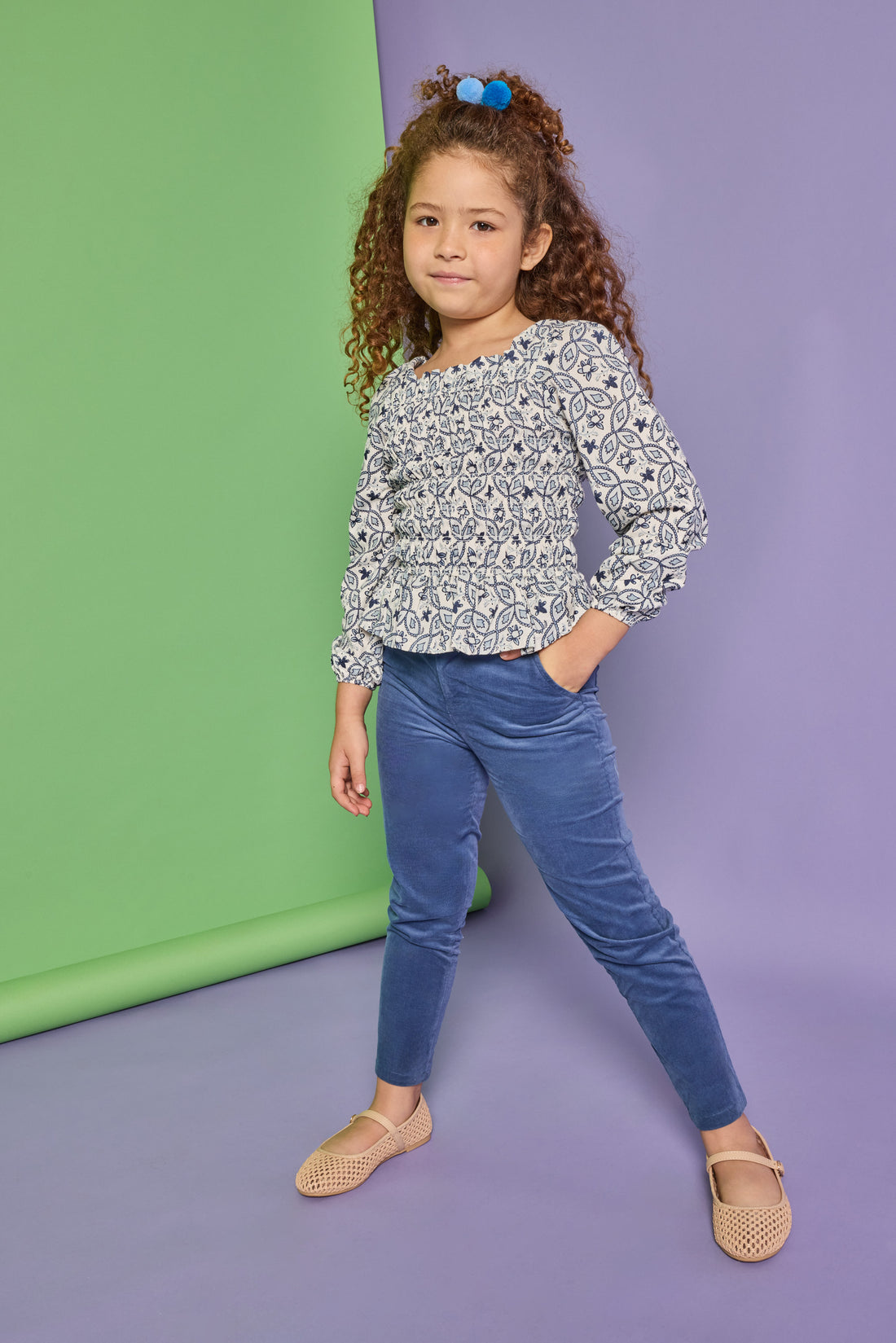 Model can be seen wearing a long sleeve woven top that features elastic ruching throughout the body of the shirt. Made of a blue and white floral print, the top pairs back perfectly with our dusty blue corduroy pants that have two pockets and button closure at waistband. 