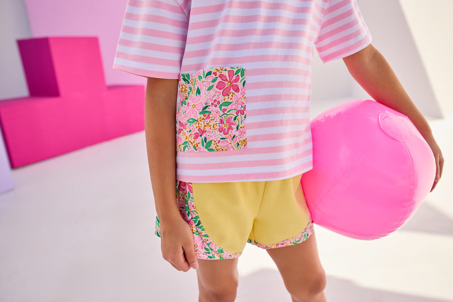 Girl/Tween model can be seen wearing a gorgeous pair of yellow knit athletic shorts that have a hot pink/yellow/green floral pattern on the trim of shorts. This floral pattern matches back perfectly with our knit pink and white stripe boxy tee that has the same floral detailing on the front faux pocket to complete the look. 