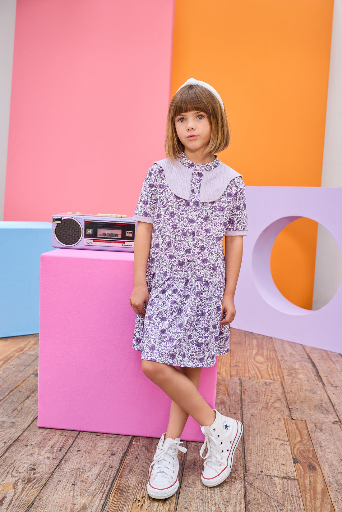 Model can be seen wearing knit dress in a gorgeous purple floral print. Dress features a purple cable knit detail at top of bust, along trim of sleeves, and dress also features button feature down front for a secure but relaxed fit. 
