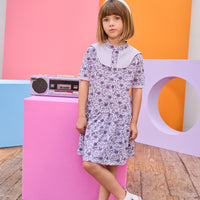 Model can be seen wearing knit dress in a gorgeous purple floral print. Dress features a purple cable knit detail at top of bust, along trim of sleeves, and dress also features button feature down front for a secure but relaxed fit. 