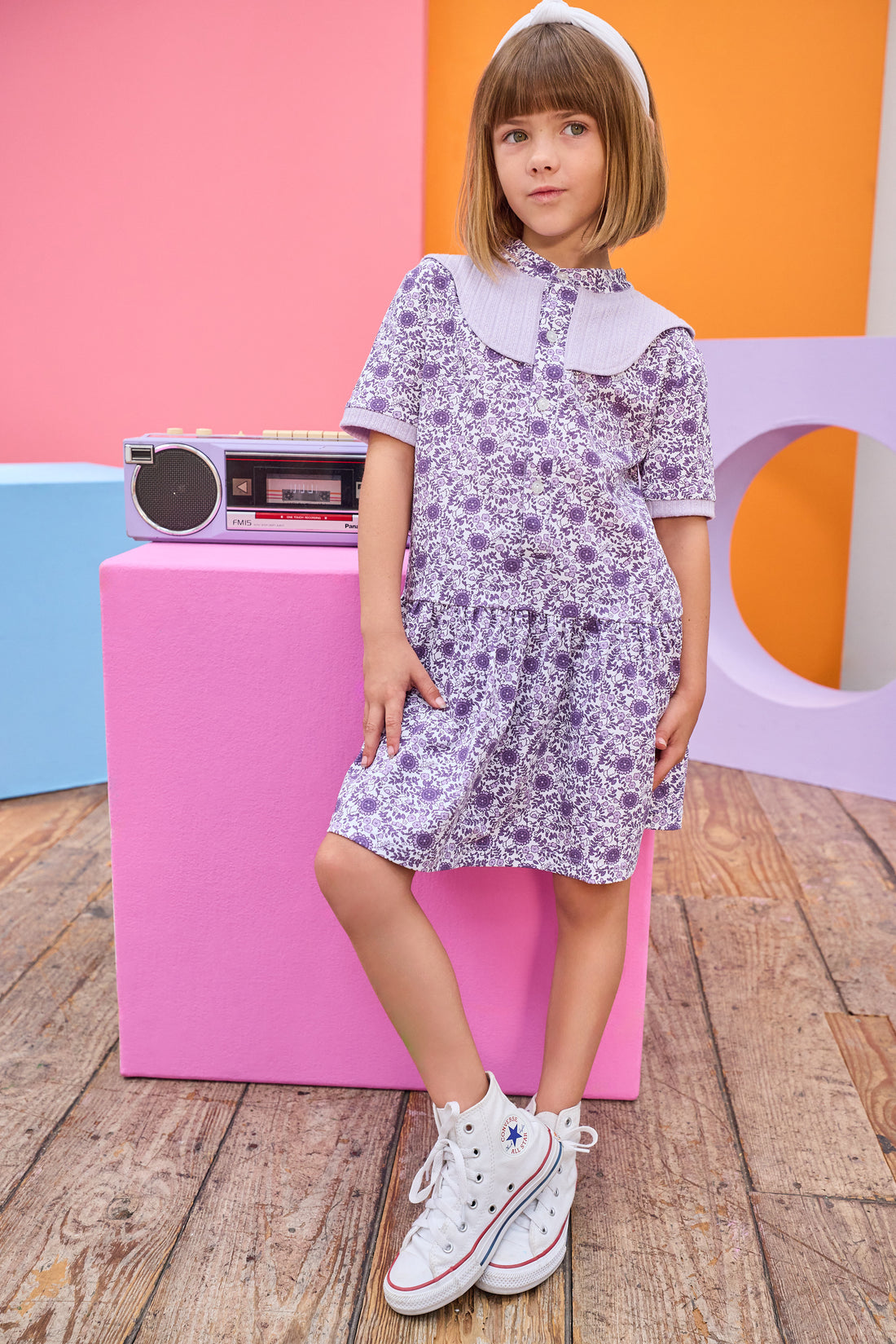 Model can be seen wearing knit dress in a gorgeous purple floral print. Dress features a purple cable knit detail at top of bust, along trim of sleeves, and dress also features button feature down front for a secure but relaxed fit. 