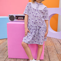 Model can be seen wearing knit dress in a gorgeous purple floral print. Dress features a purple cable knit detail at top of bust, along trim of sleeves, and dress also features button feature down front for a secure but relaxed fit. 