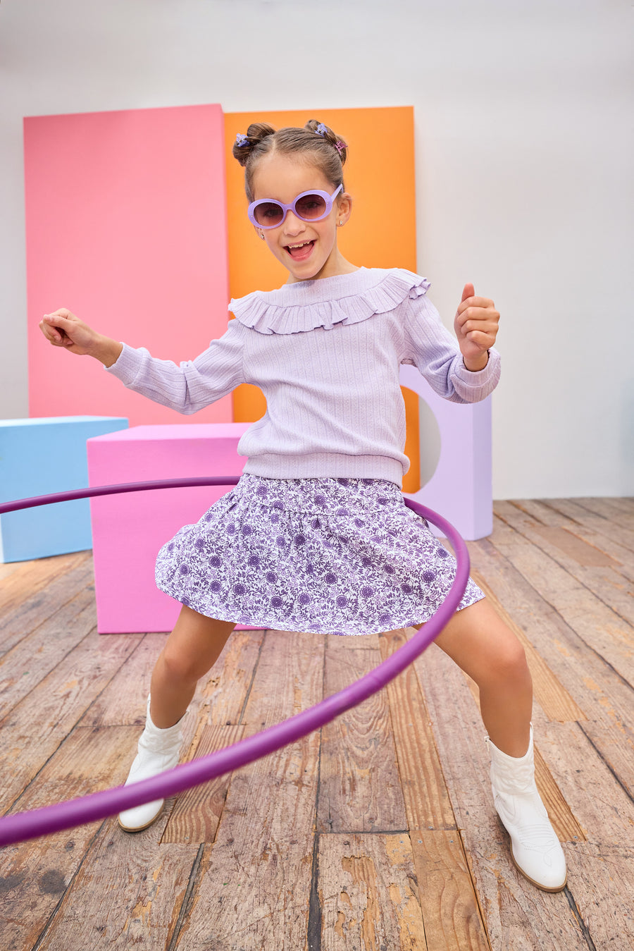 Model can be seen wearing a knit skort in a beautiful purple floral print. Skort features an elastic waistband and built in shorts for a relaxed but secure fit. Top pairs back perfectly with cable knit purple long sleeve top with ruffle detail across bust/top of sleeves to complete the look. 