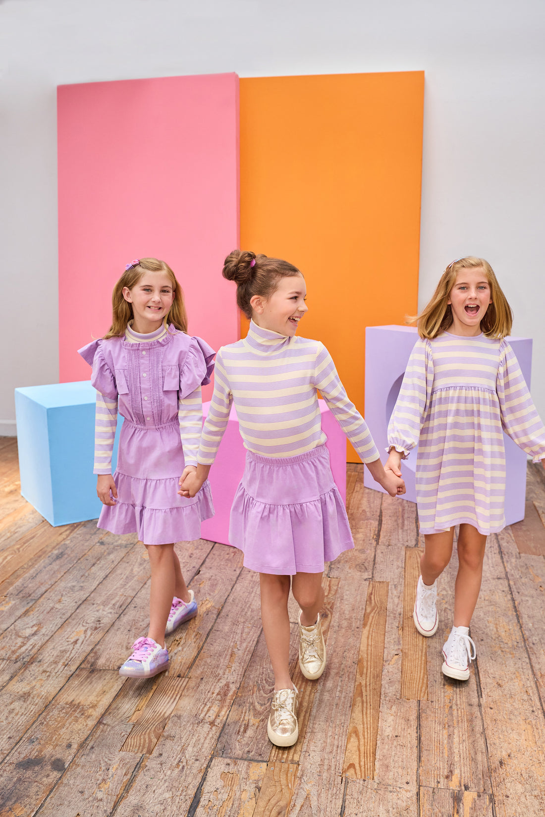 Tween girl in the middle seen wearing a lavender corduroy skirt paired back perfectly with our soft turtleneck in a lavender and cream stripe. Girls on the left and right can be seen wearing similar styles, in the same fabric, for a perfect mix and match.