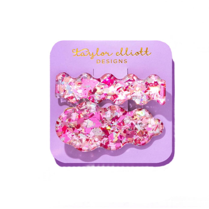 Pink glittery hair clips on a purple card