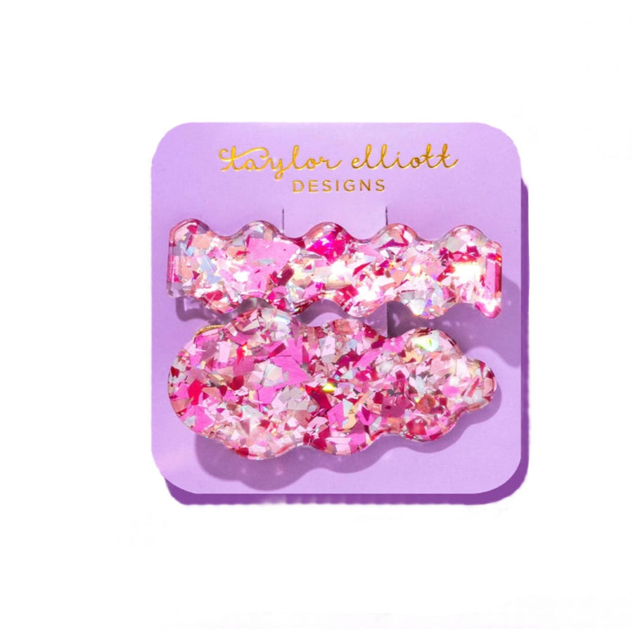 Pink glittery hair clips on a purple card