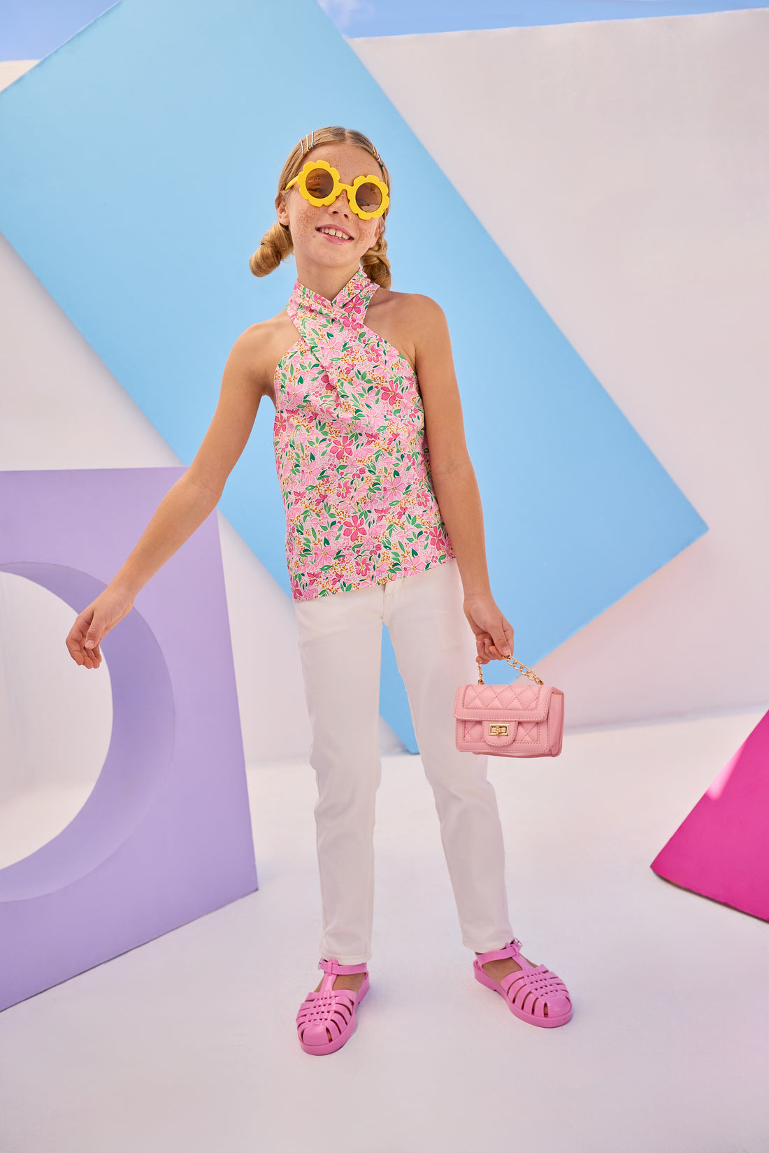 Girls/Tween woven scarf top in a beautiful hot pink floral pattern. Top features two button closure on back neckline and has a criss cross detail with the straps to create the scarf top affect. Model can be seen pairing this top back with our ivory denim jeans to complete the look. 