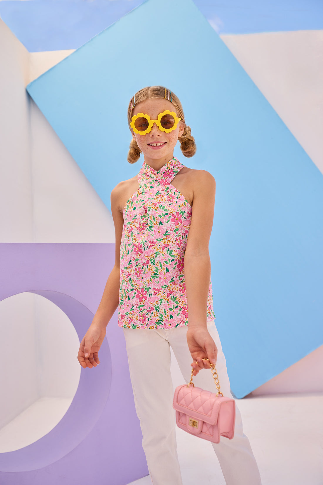 Girls/Tween woven scarf top in a beautiful hot pink floral pattern. Top features two  button closure on back neckline and has a criss cross detail with the straps to create the scarf top affect. Model can be seen pairing this top back with our ivory denim jeans to complete the look. 