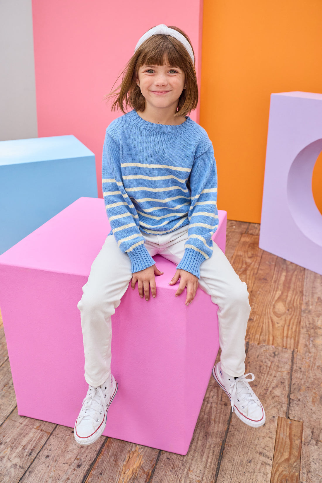 Tween model can be seen wearing blue and white stripe sweater paired back with ivory jeans to complete the look .
