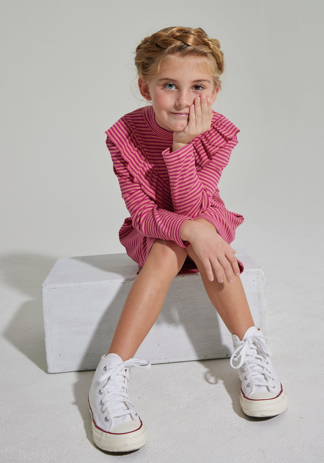 Our model can be seen wearing our Aspen Dress in Cranberry Metallic Stripe, which features the asymmetrical ruffle across top and long sleeves as well--BISBY girl