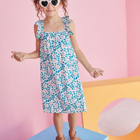Little girl wearing ruffle strap sundress which features a square neckline and a pink and green print with flowers. 