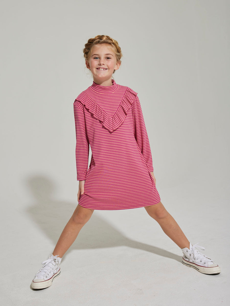 Little girl can be seen wearing out Aspen Dress in our Cranberry Metallic Stripe. It has an asymmetrical ruffle  in the front and is long sleeved as well--BISBY girl