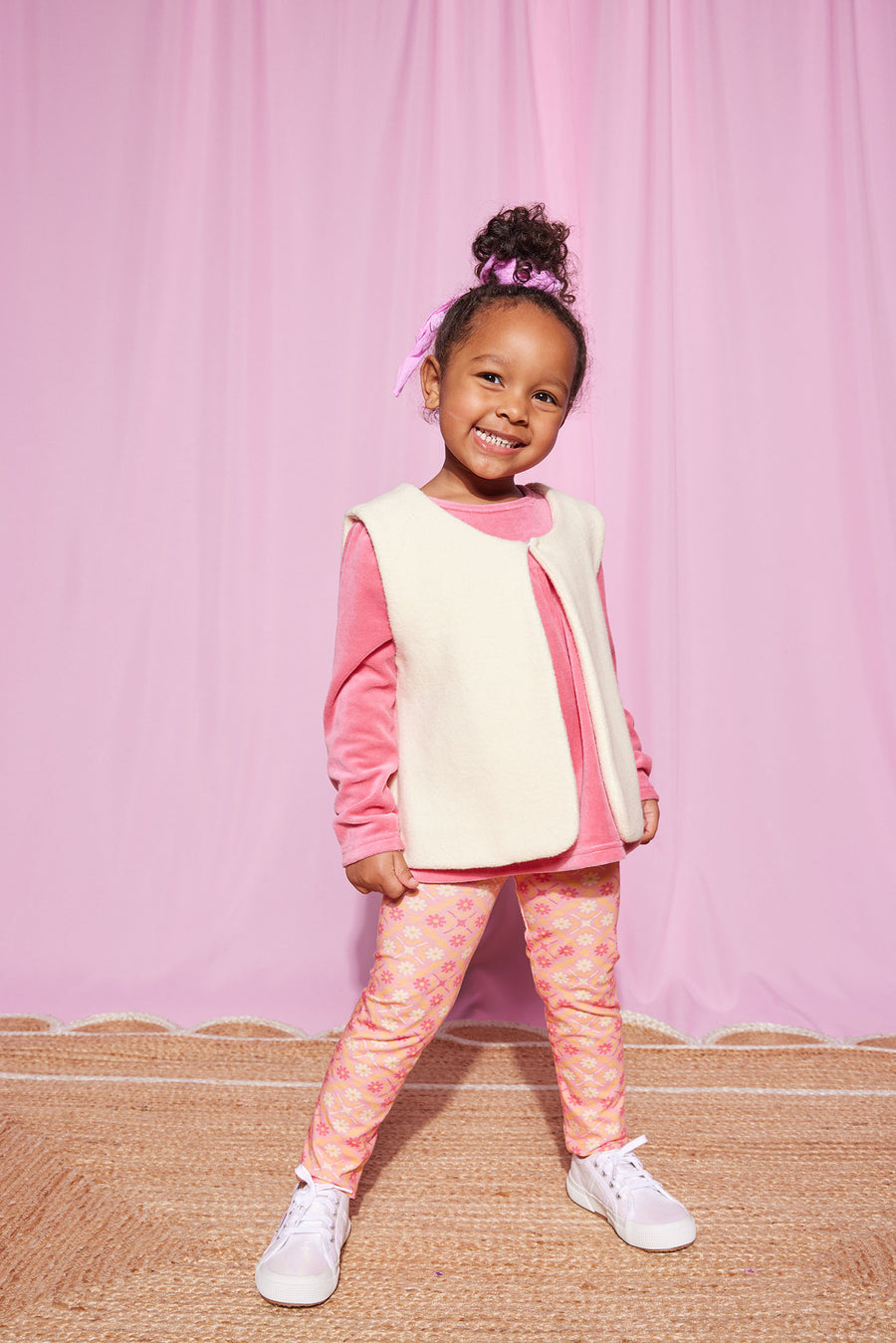 Little girl can be seen rocking our Lisle Top in Rose Velour with our Cream Sherpa Vest layered over it. She has completed the look with our Leggings in Seville Rose on the bottom--BISBY girl