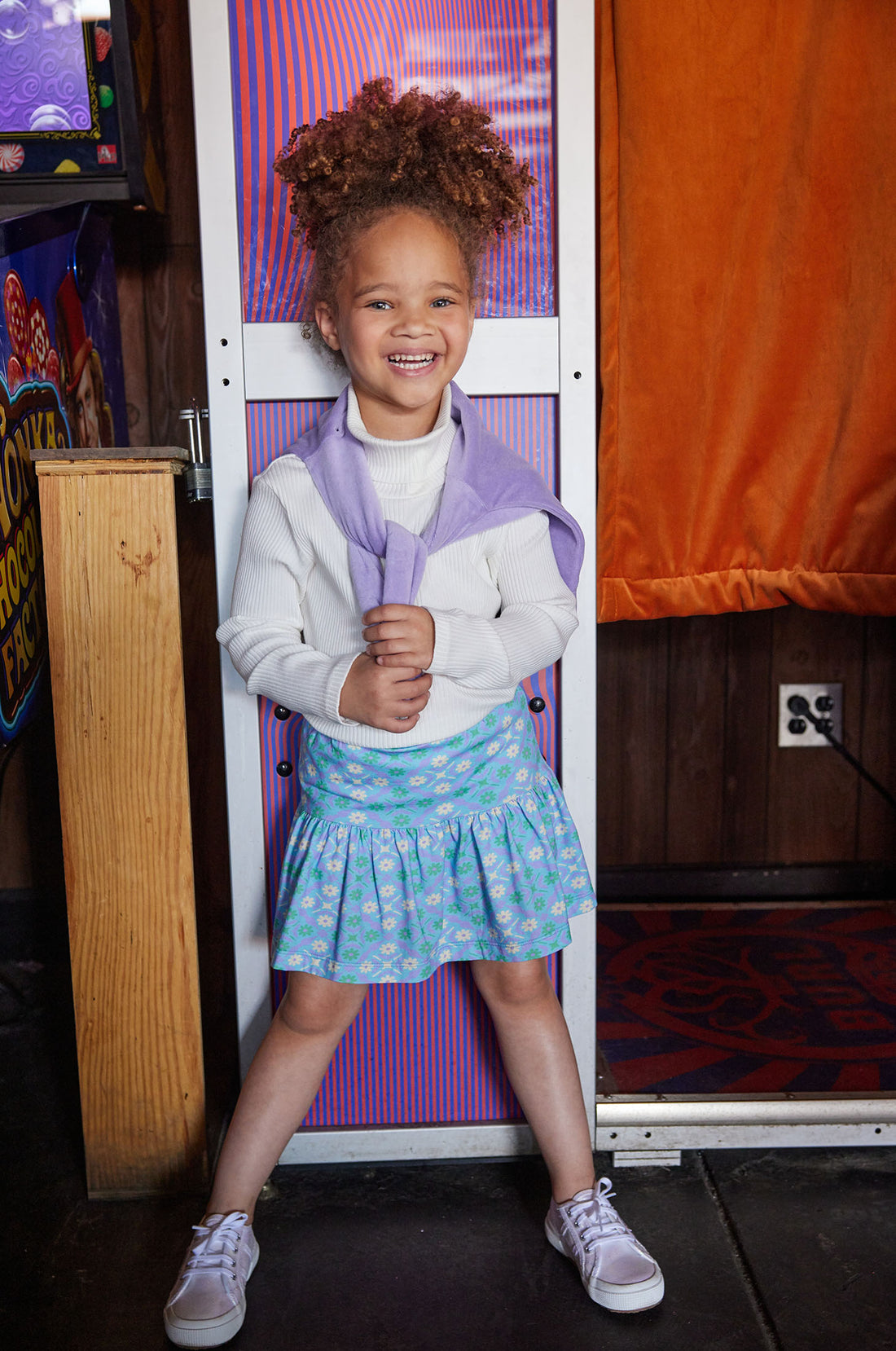 Model can be seen wearing our Sadie Skort in Seville Azul paired with our Ribbed Turtleneck in Ivory, which is layered under our Lilac Polo Pullover to complete the look--BISBY girl