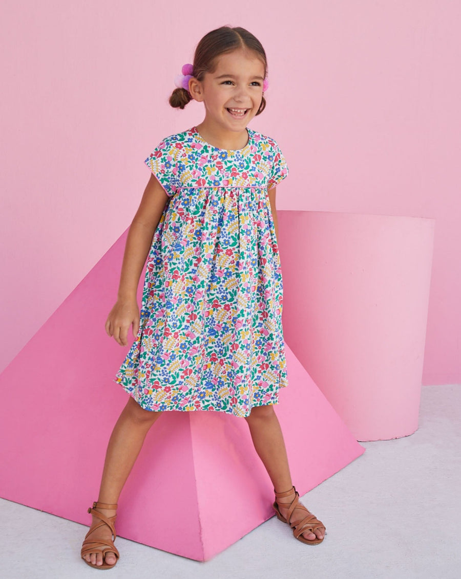 Girl wearing short sleeve dress for young girls with bright floral print. 