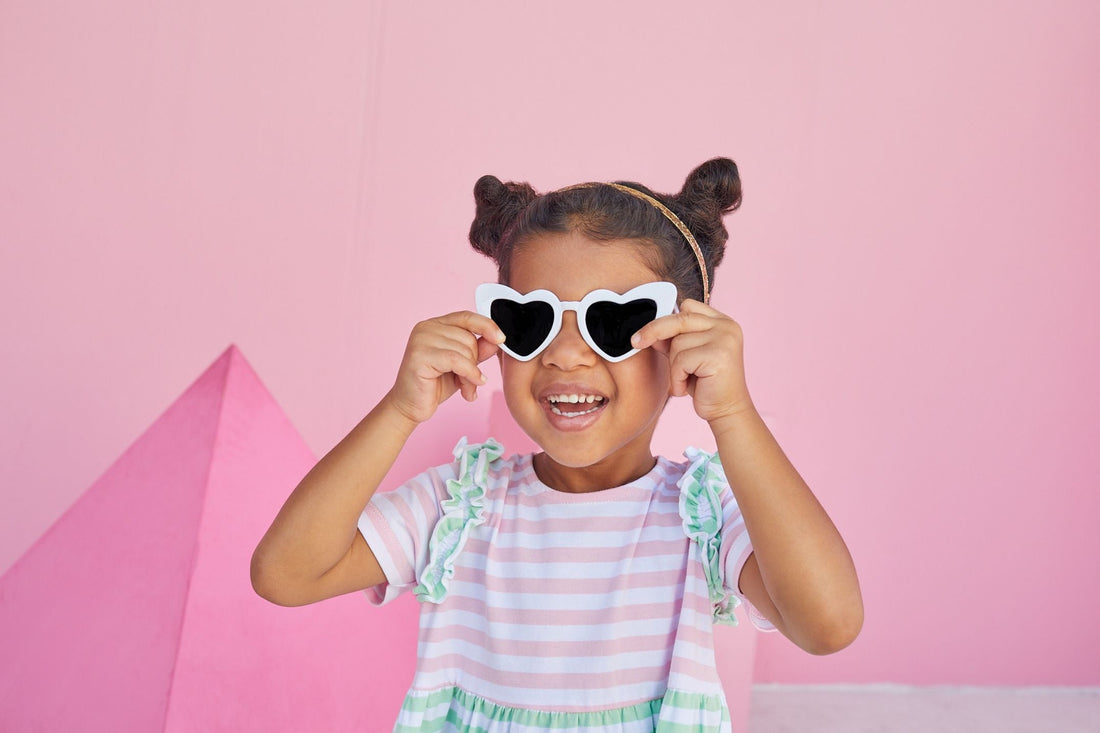 young girl wearing BISBY helen dress in pink and green stripe. 