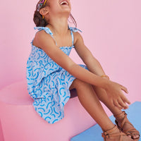 Tween girl laughing wearing BISBY Lucy Dress in blue ripple print. 