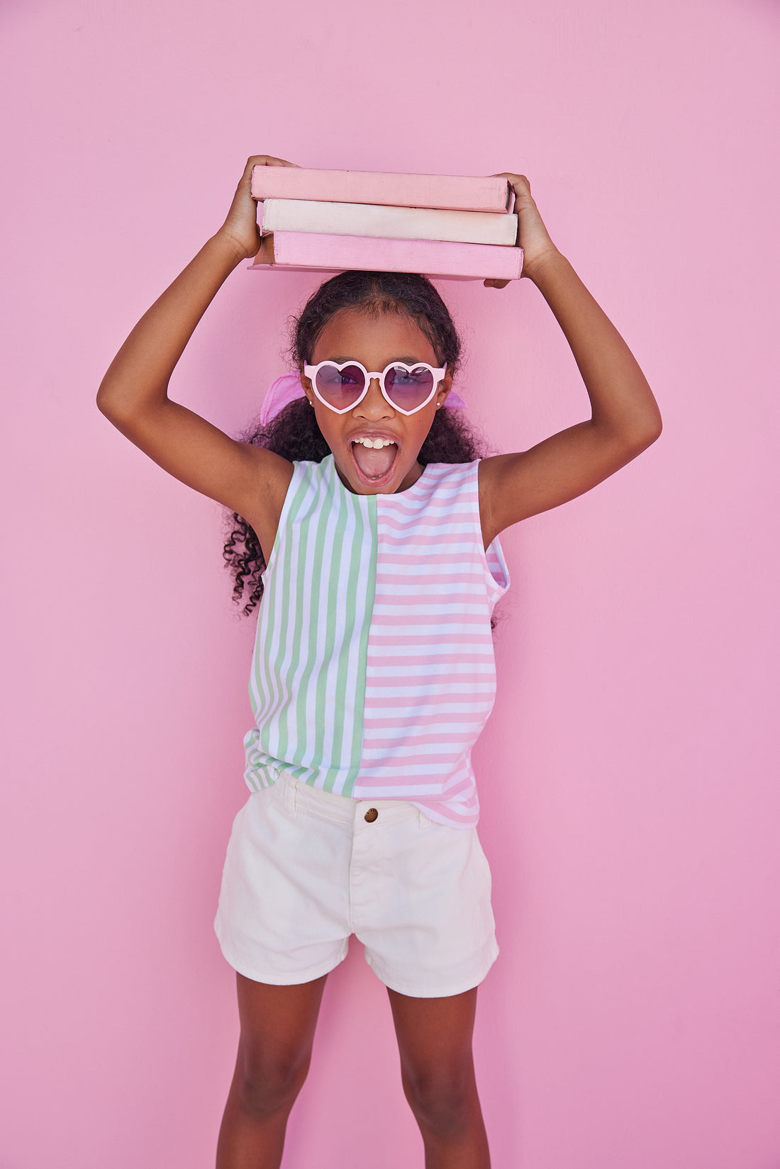 BISBY girl seen in our Green and Pink Mixed Stripe Tank which is a relaxed fitting tank with wide coverage of the shoulders. Pair it back with our denim shorts for a fun basic look.