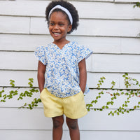 blue floral top for little girls and tweens. v-neck top with white scallop trim along sleeves and bottom of the top. Has a light blue background with white flowers