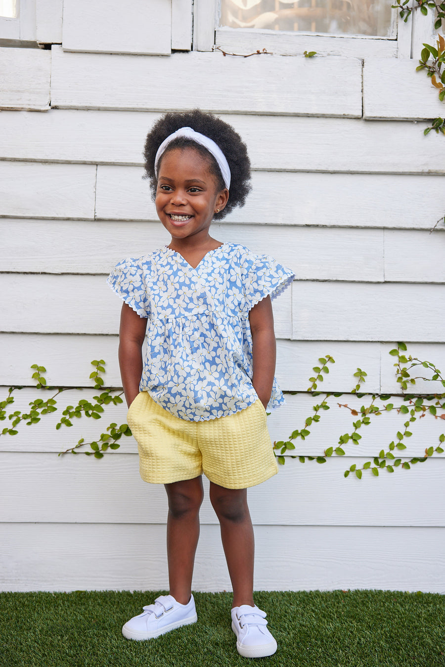 blue floral top for little girls and tweens. v-neck top with white scallop trim along sleeves and bottom of the top. Has a light blue background with white flowers