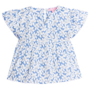 Girl/tween v-neck top with white scallop trim along sleeves and bottom of the top. Has a light blue background with white flowers with yellow centers printed on top.