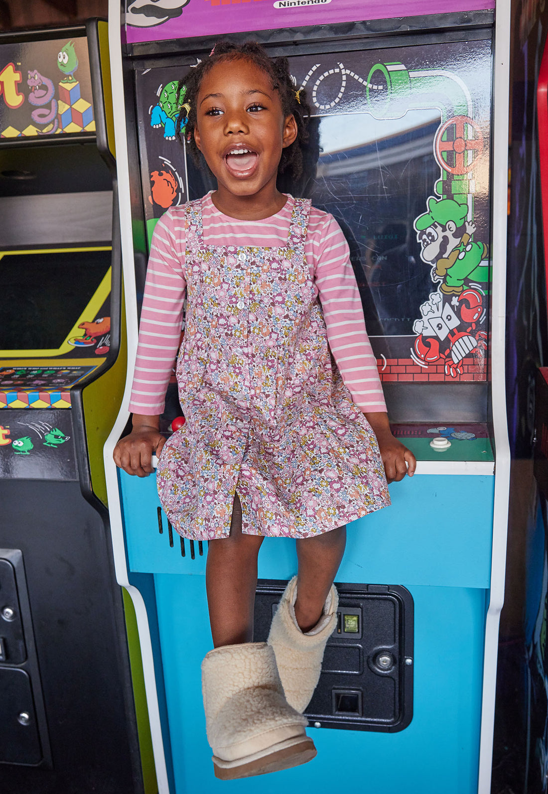 Girl seen wearing our Beatrice Pinafore - Radnor Rose Dress layered with our essential long sleeve tee (White and Pink Stripe)--BISBY girls