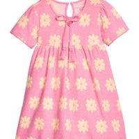 BISBY girl terry knit dress in bubblegum pink with yellow floral pattern. Dress features a keyhole button closure at back, tie tassel feature at v-neckline, and pink pom pom details at sleeve ends and bottom of dress to elevate the look. 