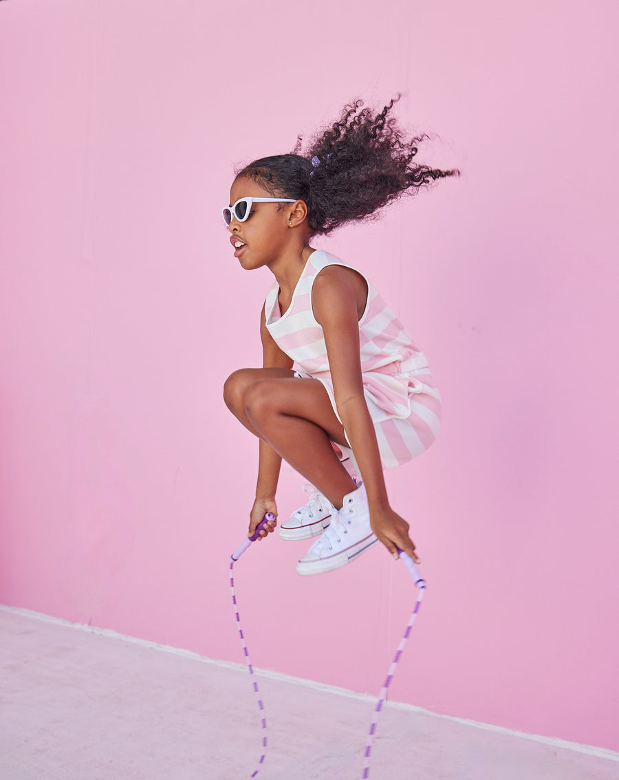 Girl/tween woven romper with pockets and elastic tie waistband with thick light pink and white stripes.