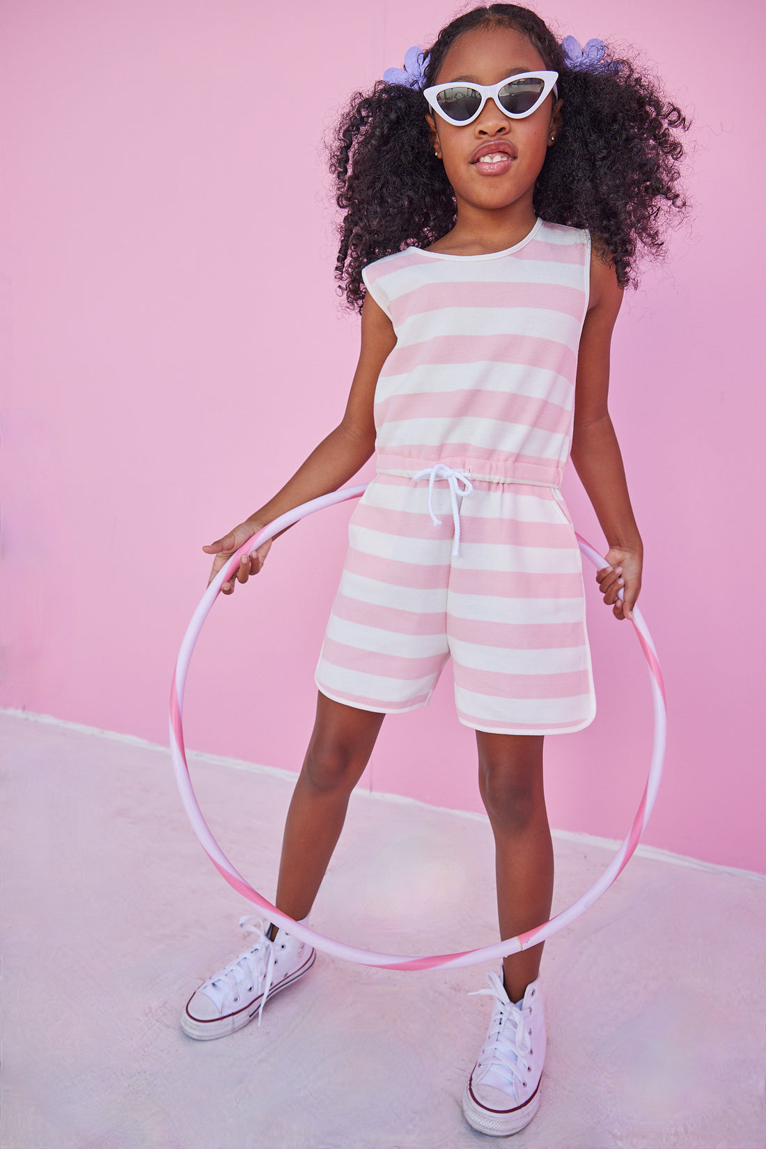 Girl/tween woven romper with pockets and elastic tie waistband with thick light pink and white stripes.