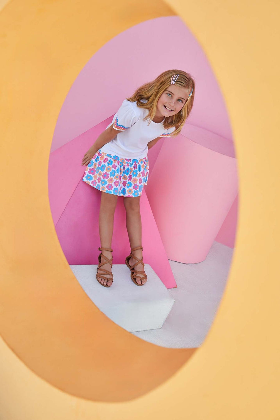 Smiling girl wearing vibrant sally skort featuring blue, pink, and orange flowers. 