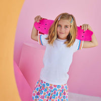 Little girl smiling and wearing our sally skort in the flower market print which has pink, blue, and orange flower print on it. The skort is knit and very comfortable. 