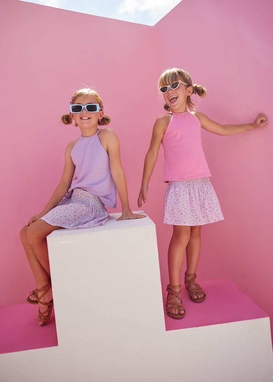 Girls can both be seen wearing our Halter Top in Pink and Lavender which feature button enclosures on the back for a secure but relaxed fit. Each girl can also be seen wearing our new Shirred Circle Skirts in our Pink and Purple Daisy Chain.