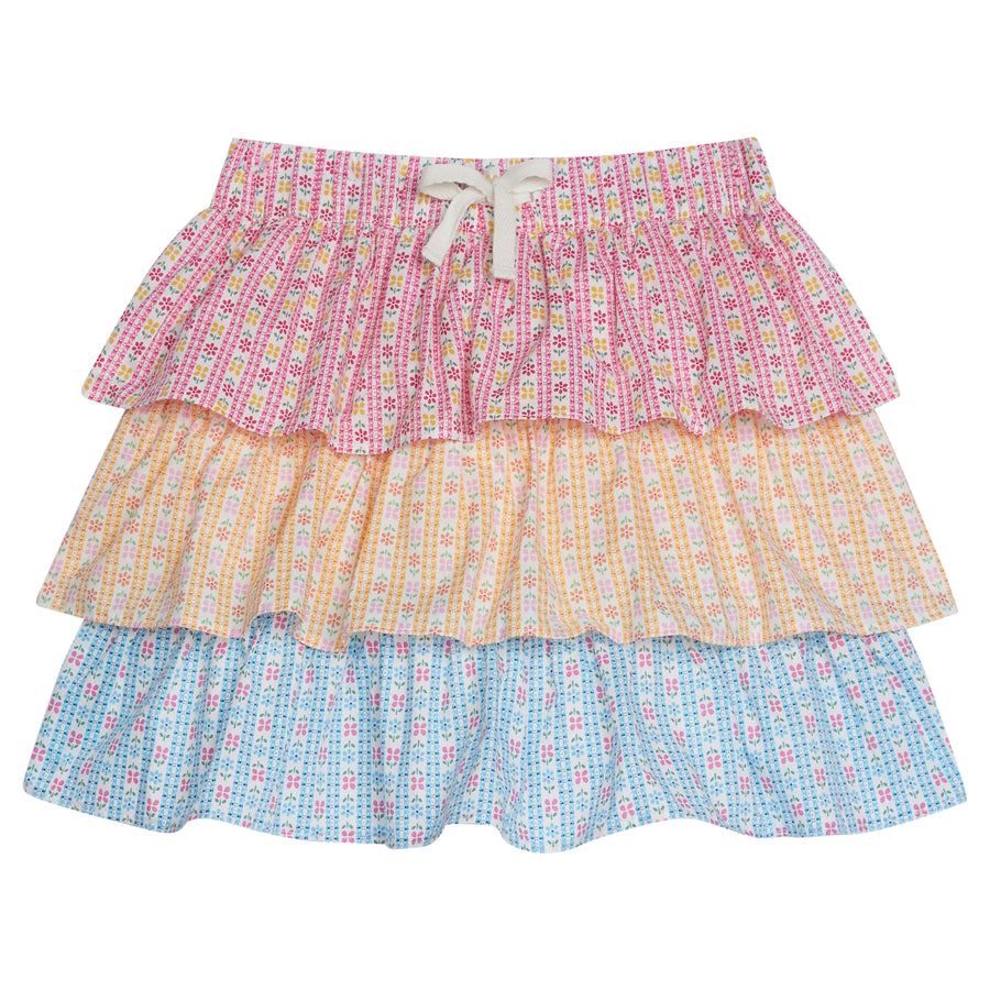 Tiered skort with built in shorts and elastic waistband with faux tie. Top tier  of skirt has pink daisy pattern, middle tier has orange daisy pattern, and bottom tier has light blue daisy pattern.