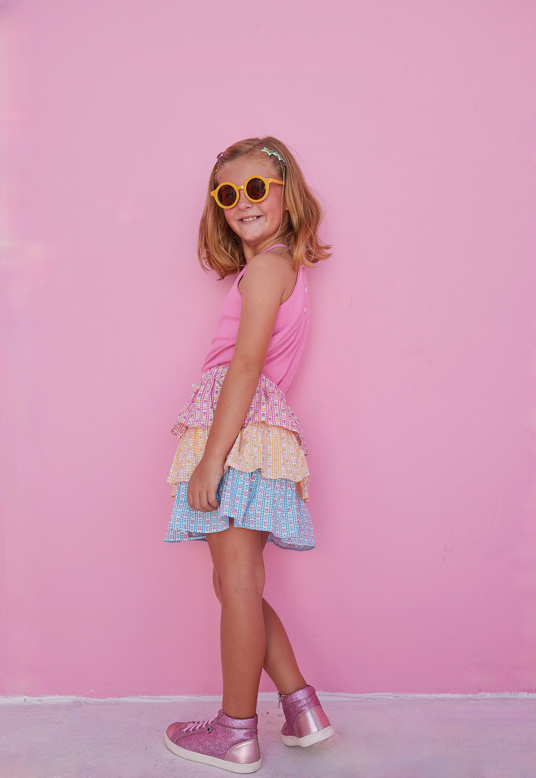 BISBY girl in our Tiered Mini Skort in our "Daisy Chain" with top tier in pink, middle tier in orange, and bottom tier in blue floral pattern. Skort has built in shorts and has elastic waistband. Paired perfectly with our Hot pink halter top  
