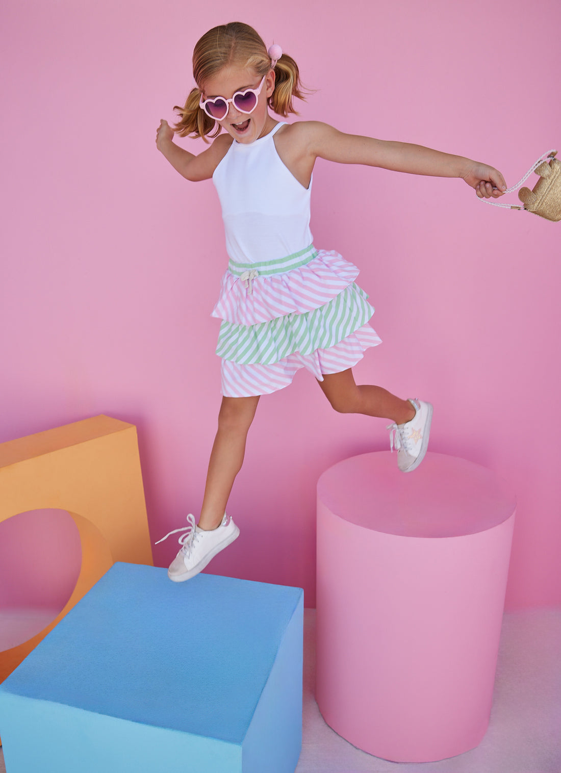 BISBY girl in our Tiered Mini Skort in Pink & Green Stripe which features pink and green tiers with a fixed tie and elastic waistband. These shorts are also perfect for your active girl because they have built in shorts as well. Pair it back with our halter top in white for a fun elevated look.