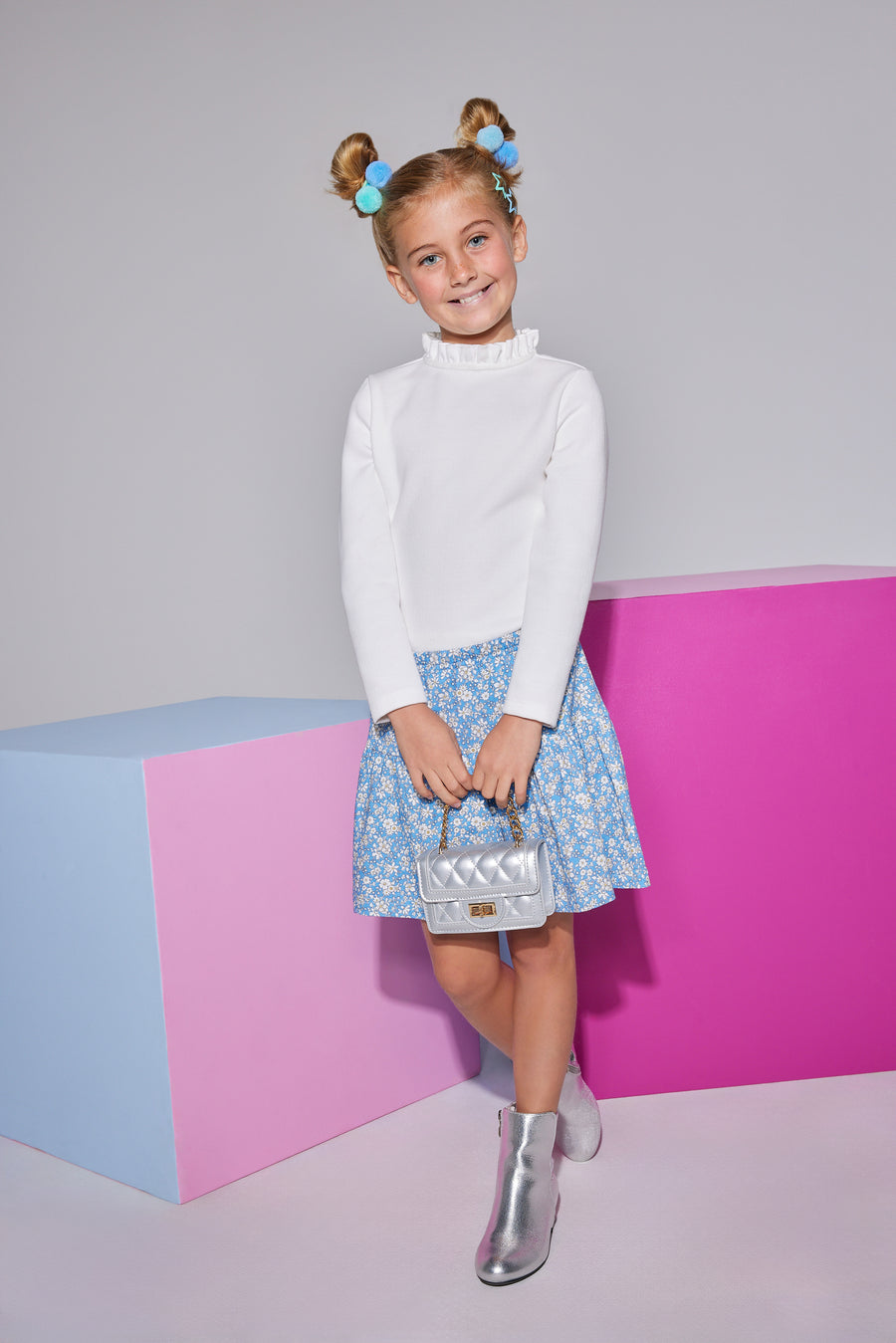 Girls/Tween knit top in white features a few button closures along the back and a ruffled neckline to add to the look. Model can be seen wearing top with our skort in a blue floral arrangement to finish off the look. 