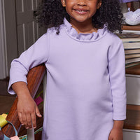 Little girl can be seen wearing our Lilac Tory Dress with ruffles around neckline--BISBY girls