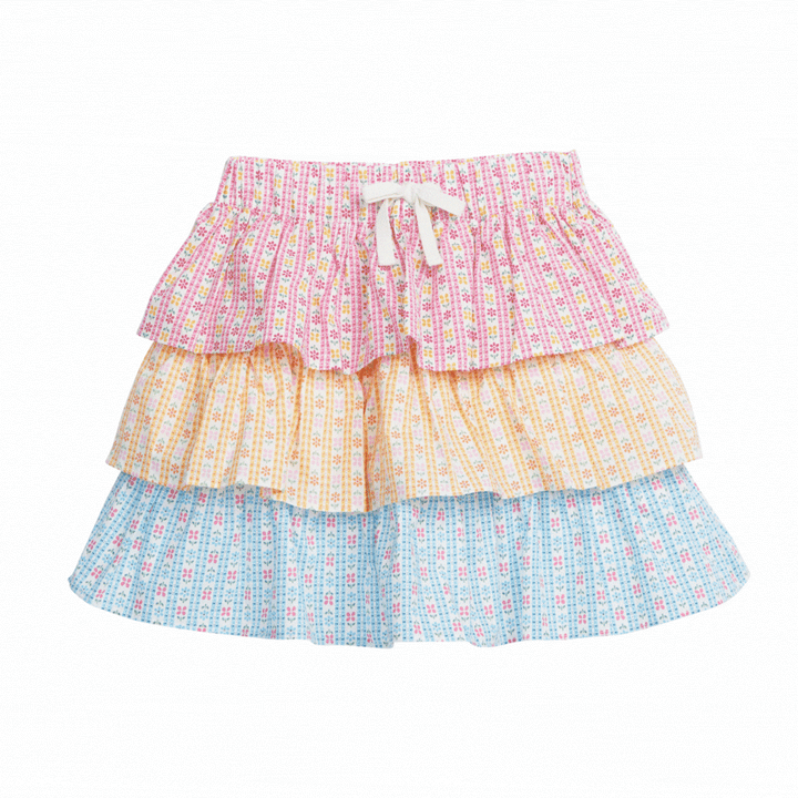 Tiered skort with built in shorts and elastic waistband with faux tie. Top tier  of skirt has pink daisy pattern, middle tier has orange daisy pattern, and bottom tier has light blue daisy pattern.