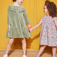 Little girls can be seen wearing two popular dresses. On left, wearing our Sage Corduroy Western Styled dress paired with tan turtleneck (left) and the other little girl wearing the Charlotte Merion Floral Dress--BISBY girl