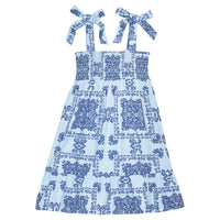 BISBY girl woven dress in a light blue/navy blue bandana print. Dress features wide straps with faux bow tie feature, smocking across bust, and bottom tier feature for an elevated look.